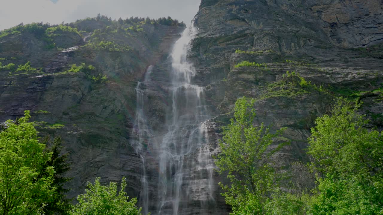 impresionante toma estática de una majestuosa cascada que fluye por la montaña en la región suiza