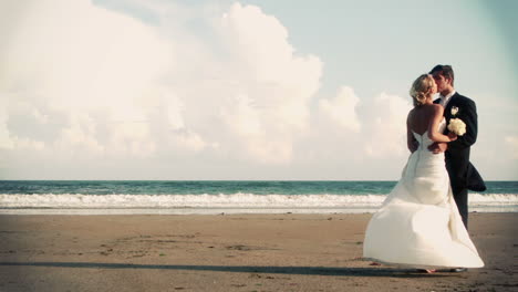 attractive newlywed couple kissing on the beach in cinemagraph