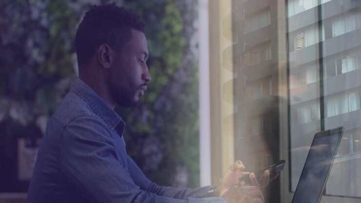 Animation of african american businessman using computer over data and cityscape