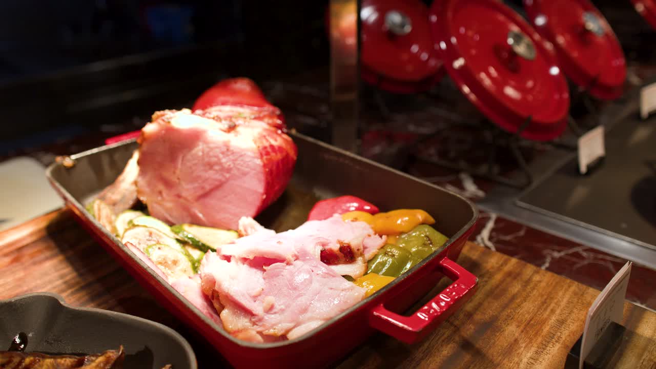Nærbillede af skiveskåret stegt skinke med squash og peberfrugter på en buffet