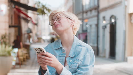 upset young woman using cellphone typing browsing loses becoming shocked bad news on city street