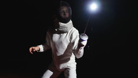 a woman fencer in a white uniform with a sword in her hand stands on a dark background.