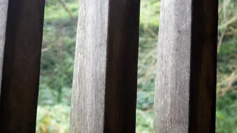 Raining-weather-in-rural-mountain-countryside-through-rustic-oak-wood-barn-beams-window-dolly-left-shot