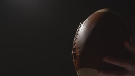 close up studio shot of american football player holding ball with low key lighting 3