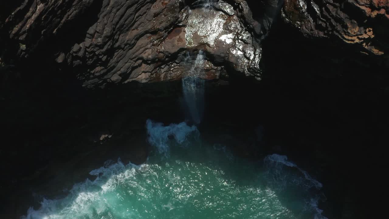Top down aerial view toward waterfall flowing into Indian Ocean