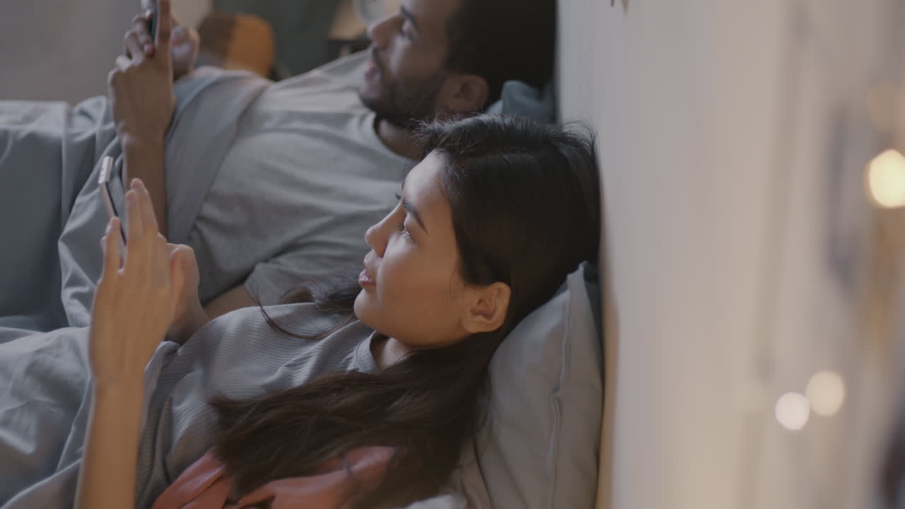 Coppia che usa il telefono a letto di notte