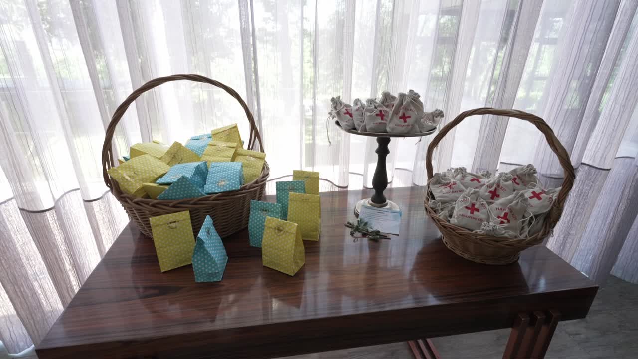 Wedding favor table with wicker baskets, colorful gift bags, and first-aid pouches