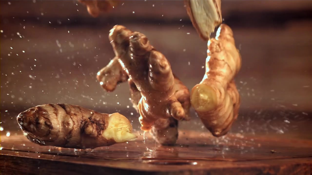 Fresh Ginger Roots Falling onto Wet Wooden Surface in Slow Motion
