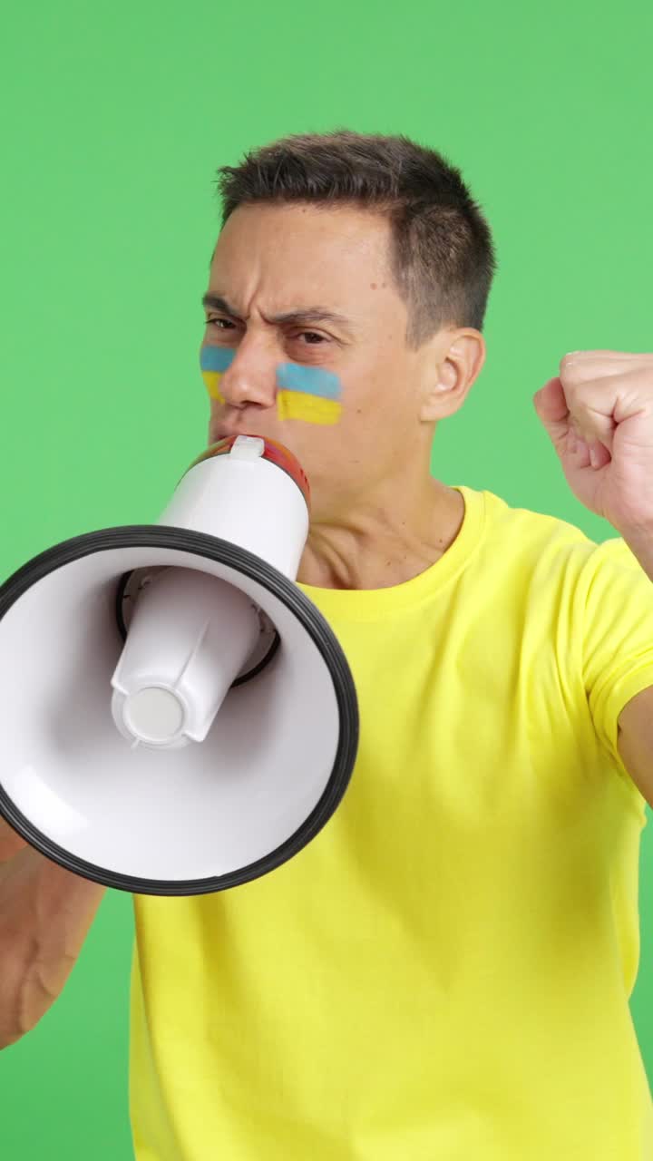 Excited man with ukrainian flag on face using a megaphone