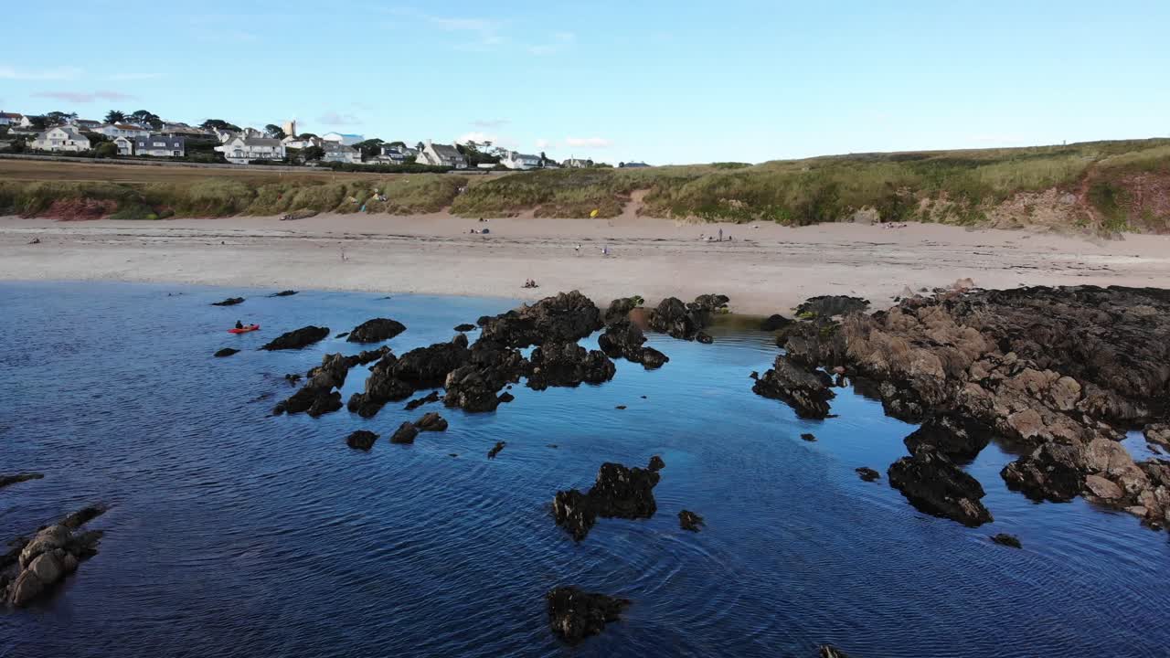 avión volando sobre rocas de marea baja al lado de la playa en thurlestone
