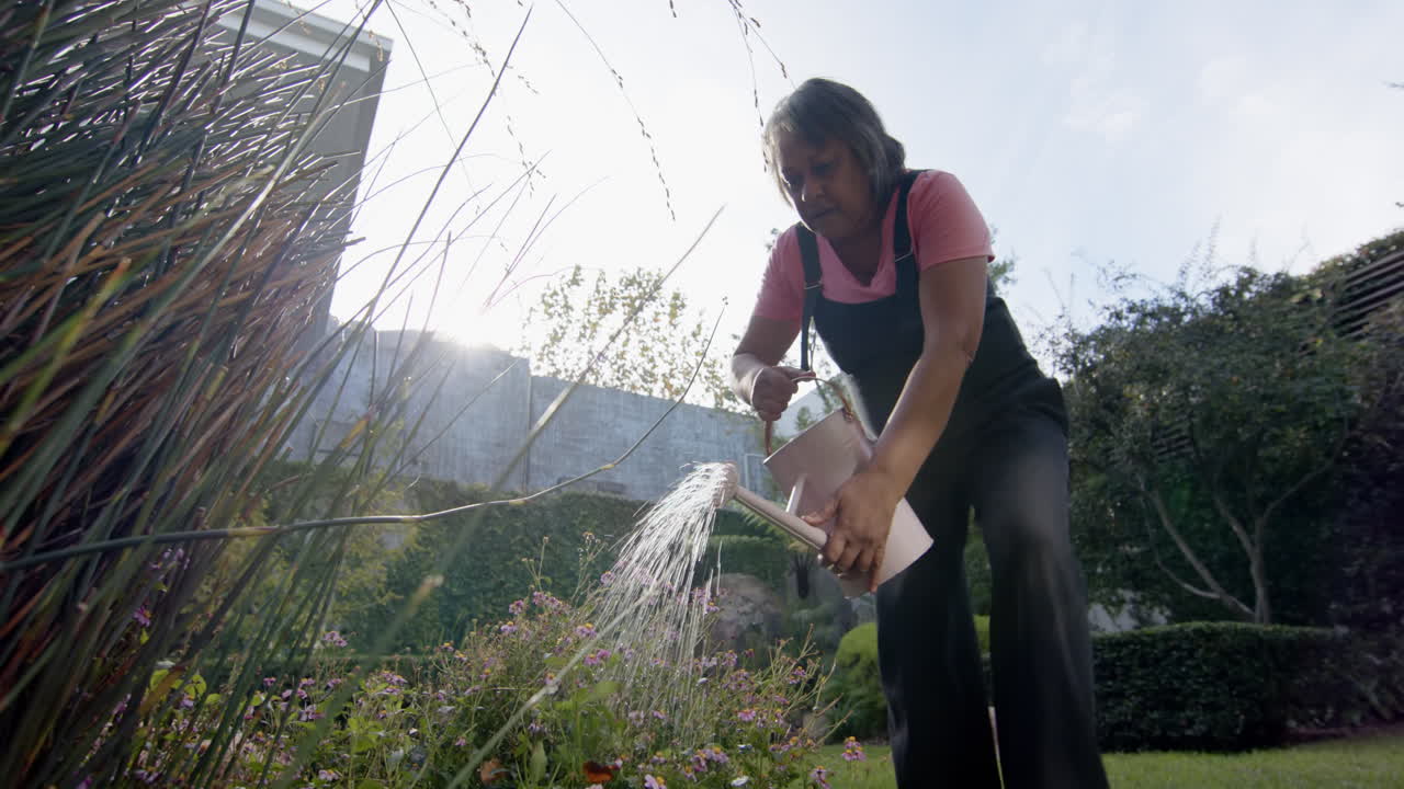 Watering garden plants, senior woman enjoying outdoor gardening, copy space