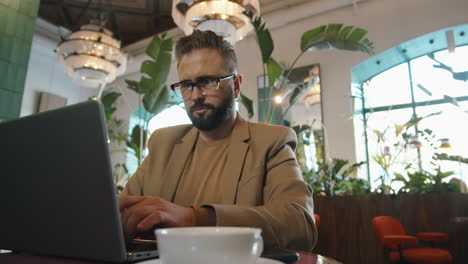 caucasian businessman working on laptop in cafe