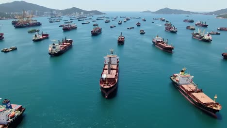 aerial view of numerous cargo ships docked in calm waters, highlighting maritime activity and transportation in a busy port environment