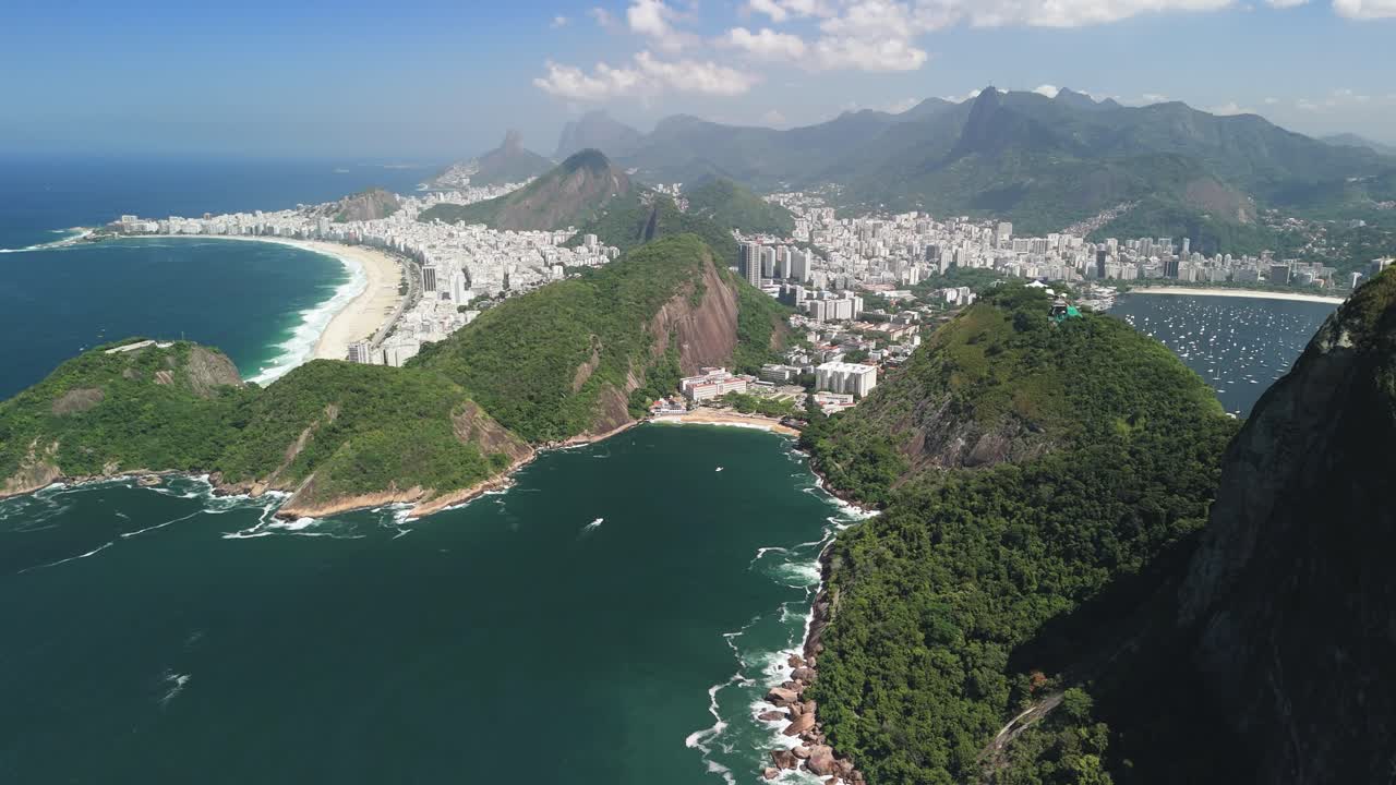 Drone ascends, panning left across sunny Copacabana Beach with Sugarloaf and bay vistas