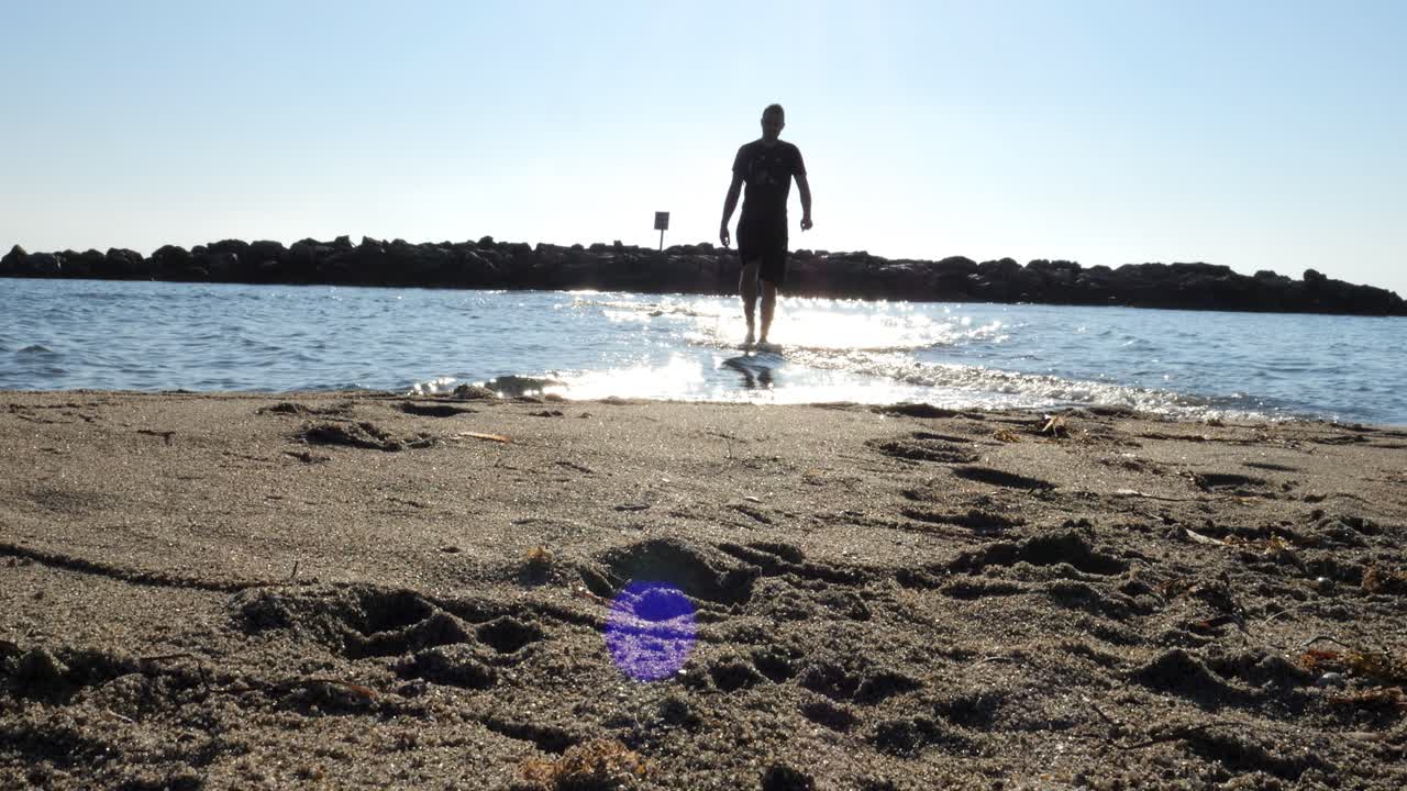 휴가 기간 동안 여름 아침과 아름다운 모래를 바라보는 조용한 파도와 함께 바다에서 나오는 휴가객의 낮은 각도  ⁇