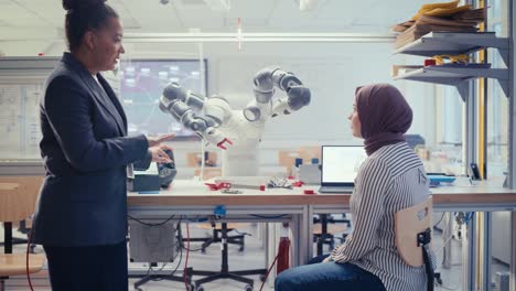 Skilful Black Specialist Explain to Arabic Computer Science Specialist While Robot Limb Moving Under her Controlling. People Designing Automated Robotic Systems Concept