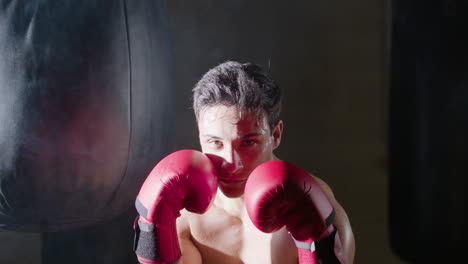 young male boxer stepping out from the dark background
