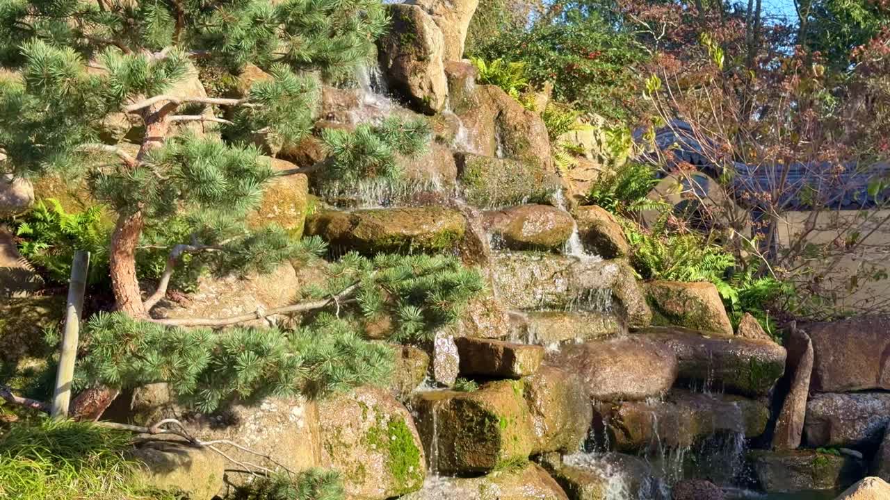Nahaufnahme eines Wasserfalls in einem chinesischen Garten, bei dem die Wasserströmung in Rennes allmählich langsamer wird