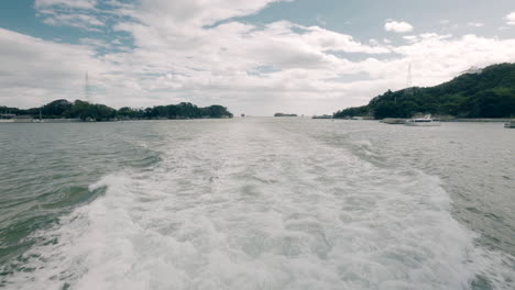 Foamy-Wake-Behind-A-Boat-Sailing-Across-The-Sea-In-Sendai,-Japan-With-Seagull-Flying-Above-Water-Surface