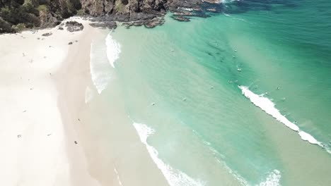 Drohnenantenne,-Die-Nach-Unten-Schwenkt,-Um-Surfer-Zu-Sehen,-Die-An-Einem-Wunderschönen-Strand-Mit-Blauem-Wasser-Wellen-Fangen