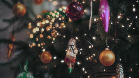hand hanging red bauble on christmas tree at home