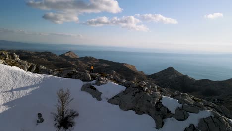 man hiking on mountain ridge trail against adriatic landscape.  winter sunny and snowy day.
