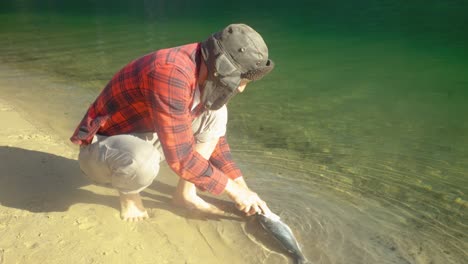 disparo en cámara lenta de un pescador escalando un gran salmón en una playa