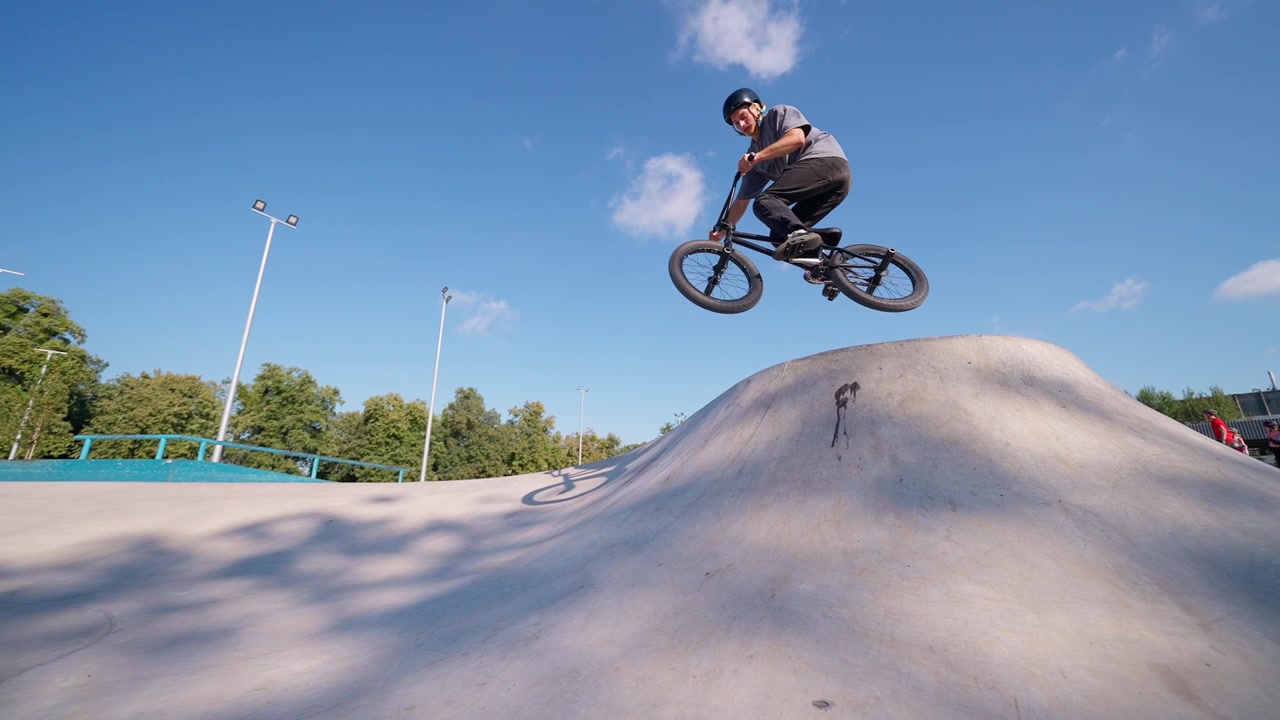 BMX-rytter udfører et spring-trick i en beton-skatepark