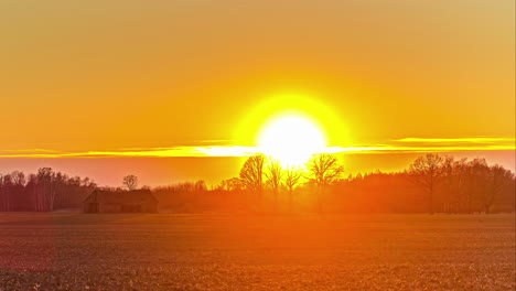 scenic view on the countryside with fiery and vibrant sun setting on the horizon until calm sunrise