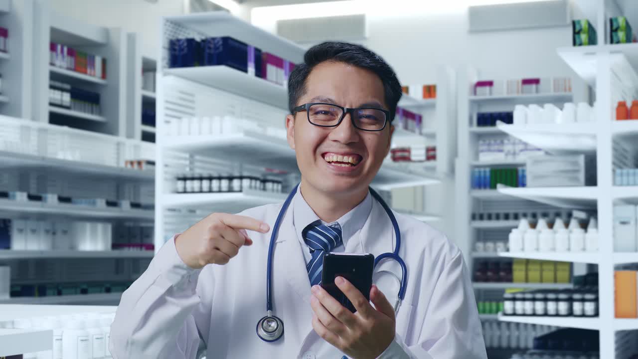 약국에서 스마트폰을 가리키는 스테토스코프를 가진 아시아 남성 의사의 클로즈업