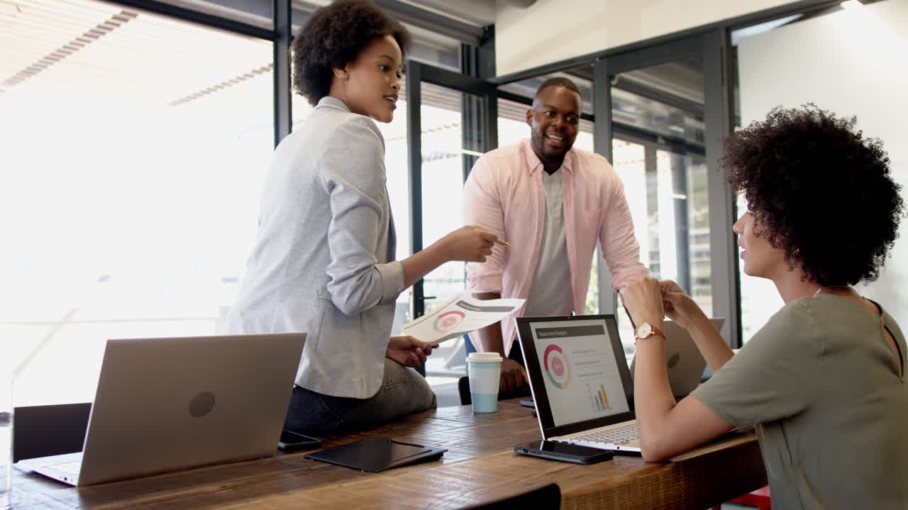 Business colleagues brainstorming, discussing charts and graphs in modern office
