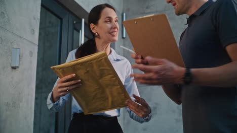 woman receives package from delivery person and signs for it