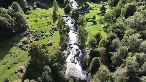 Rustic-Foroglio-houses-by-the-cascading-stream-waterfall,-Maggiatal,-Tessin,-Switzerland---aerial