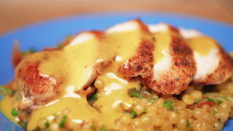 macro pull back view of maple dijon chicken breast on a bed of couscous covered in thick, rich gravy