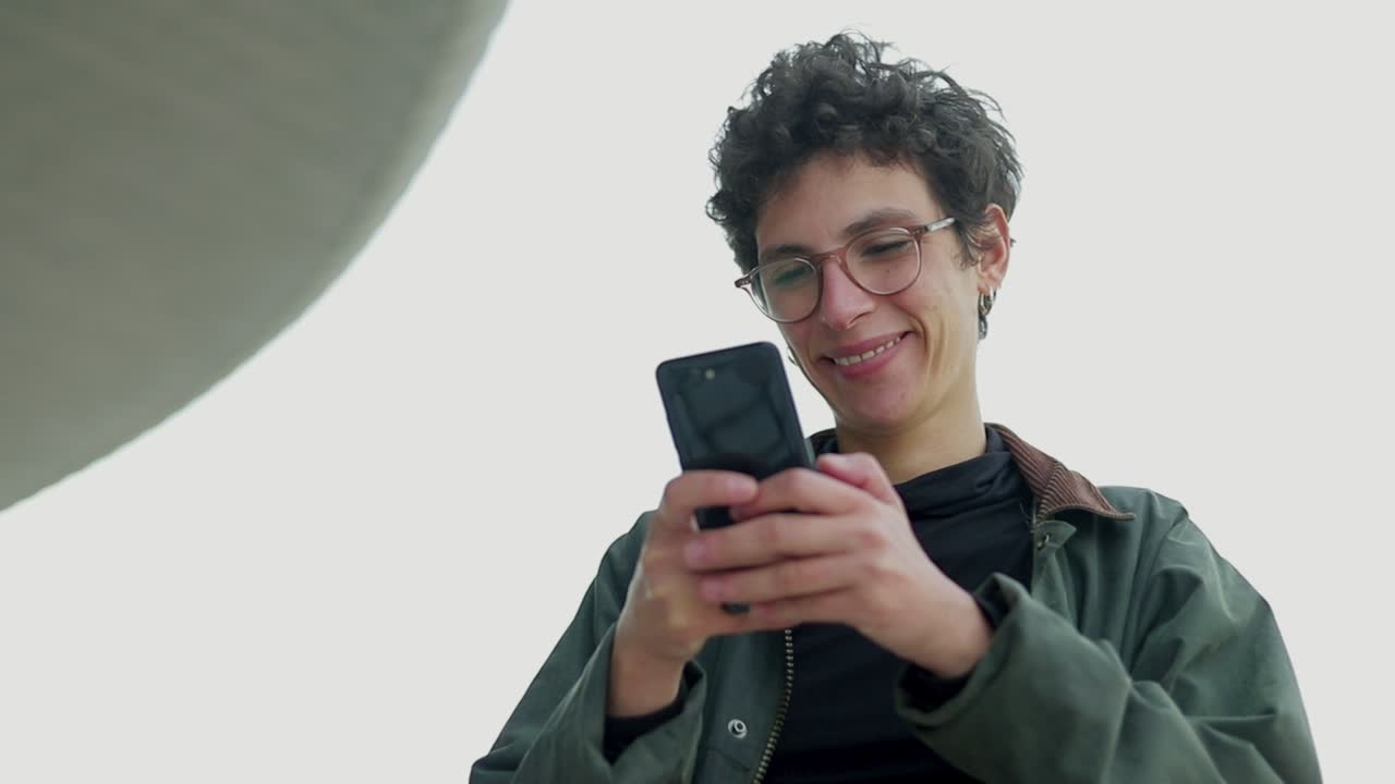 mujer feliz con gafas usando teléfono celular al aire libre