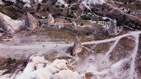 vuelo aéreo sobre el valle de kizilcukur que muestra 2 caballos galopando en un camino de tierra, capadocia
