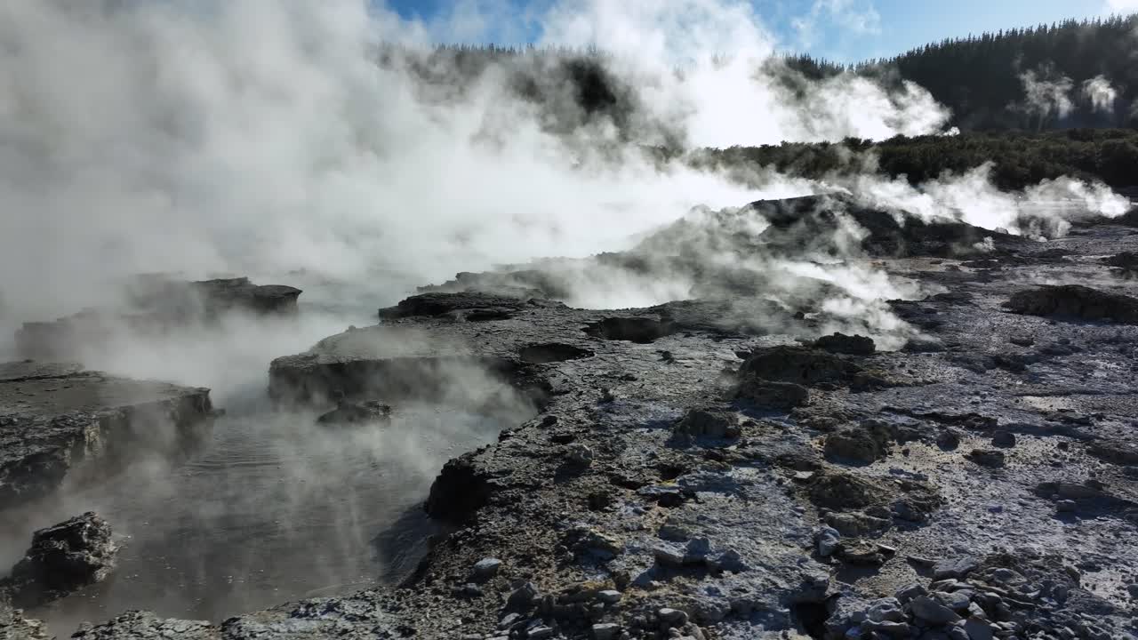 Drone slowly flying over geothermal bubbling mud landscape. Trees, steam, bubbling mud and steam. Alien Landscape. Sci-fi. Global Warming