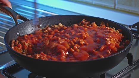 cooking and stirring spicy ground turkey with beans and tomato sauce