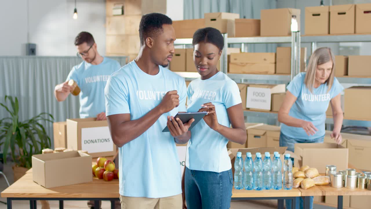 African American young male and female volunteers typing on tablet