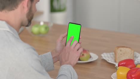 vista trasera de un joven usando un teléfono inteligente con pantalla clave cromada