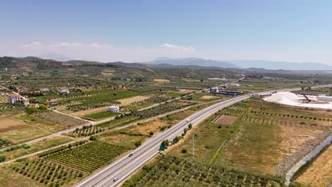 Highway road in rural area in the balkans with cars driving through and olive trees nearby
