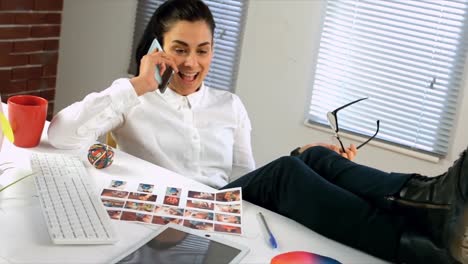 Business-woman-at-her-desk-talking-on-cell-phone-with-feet-on-desk