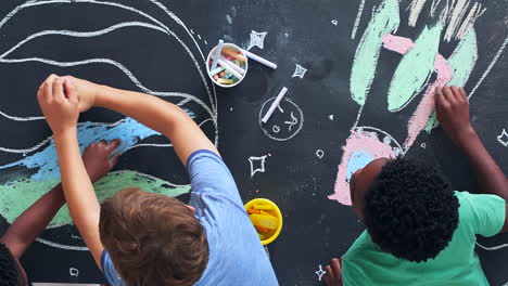 children drawing space themes on a blackboard