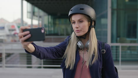 retrato de una joven hermosa mujer de negocios rubia pasante sonriendo posando haciendo caras tomando fotos selfie usando la cámara del teléfono inteligente en la ciudad