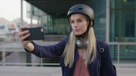 portrait of young cute blonde business woman intern smiling posing making faces taking selfie photo using smartphone camera in city