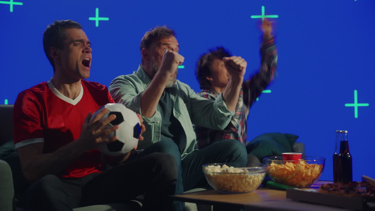 en casa, tres fanáticos felices sentados en un sofá ven el juego en la televisión con pantalla verde en el fondo de la llave de croma. celebren la victoria del campeonato del equipo deportivo. un grupo de amigos animan al club favorito.
