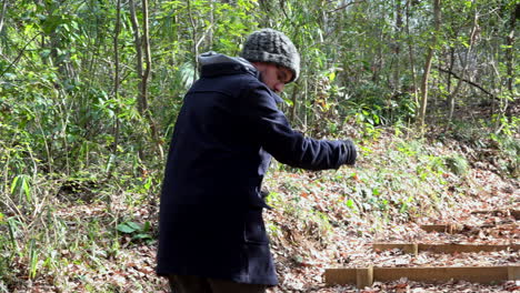 an adult male climb stairs holding something in his hand in a forest on daytime