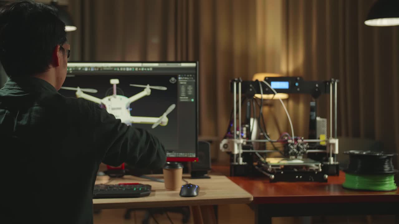 Back View Of Asian Engineer Stretching While Work On Personal Computer And 3D Printer, Screen Shows Cad Software With 3D Prototype Of Drone Delivery