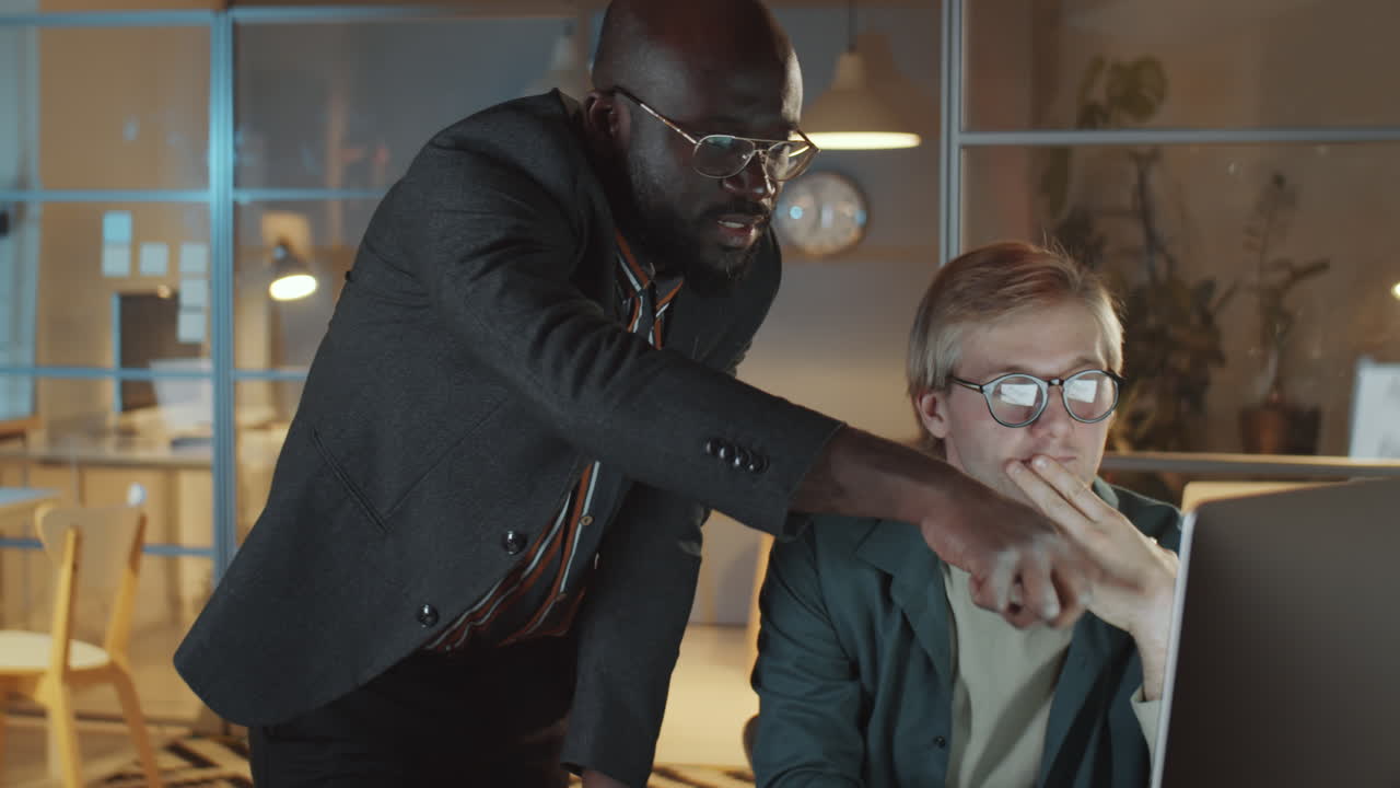 compañeros de trabajo discutiendo un proyecto en la computadora en la oficina nocturna