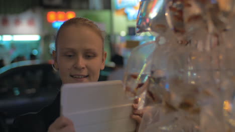 Young-blond-woman-take-a-picture-of-gold-aquarium-fishes-packed-in-plastic-bag-Hong-Kong-China